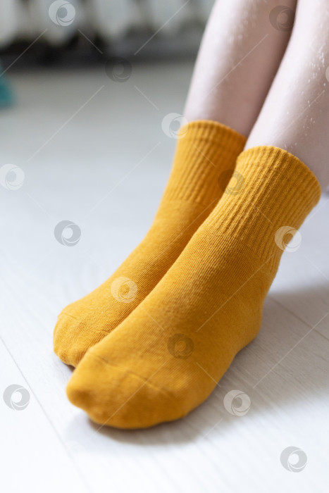 Скачать Детские ножки в желтых носочках на белом фоне фотосток Ozero