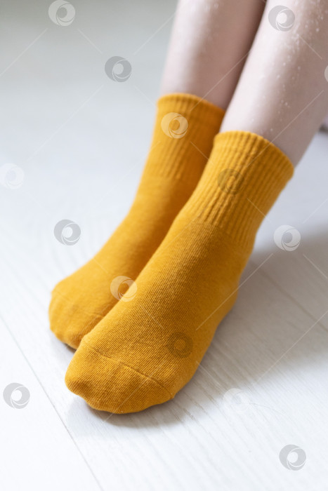 Скачать Детские ножки в желтых носочках на белом фоне фотосток Ozero