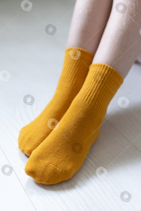 Скачать Детские ножки в желтых носочках на белом фоне фотосток Ozero
