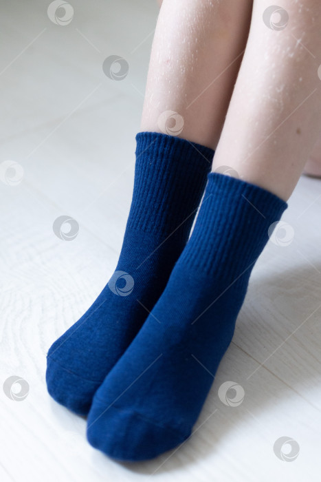Скачать Детские ножки в синих носочках на белом фоне фотосток Ozero