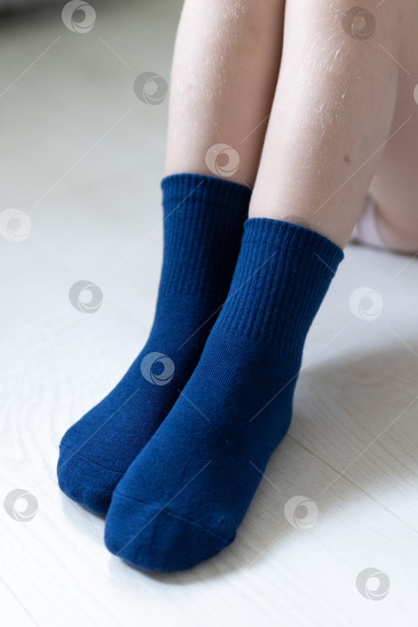 Скачать Детские ножки в синих носочках на белом фоне фотосток Ozero