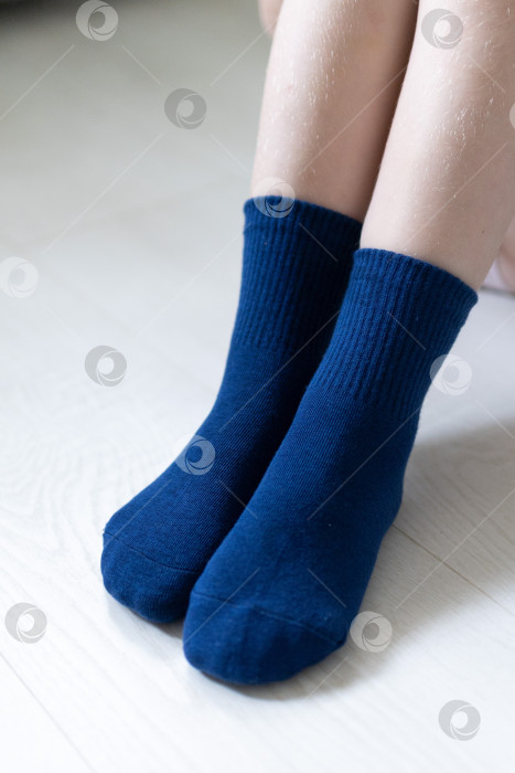 Скачать Детские ножки в синих носочках на белом фоне фотосток Ozero
