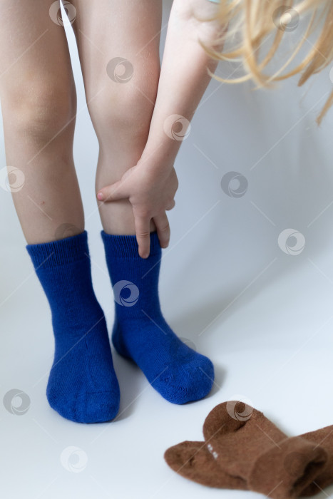 Скачать Детские ножки в синих носочках на белом фоне фотосток Ozero