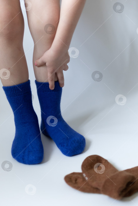 Скачать Детские ножки в синих носочках на белом фоне фотосток Ozero