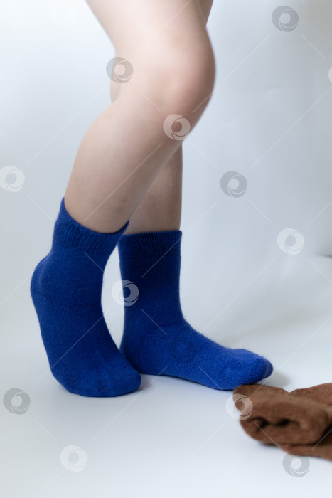 Скачать Детские ножки в синих носочках на белом фоне фотосток Ozero