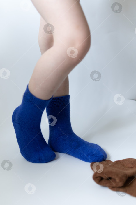 Скачать Детские ножки в синих носочках на белом фоне фотосток Ozero
