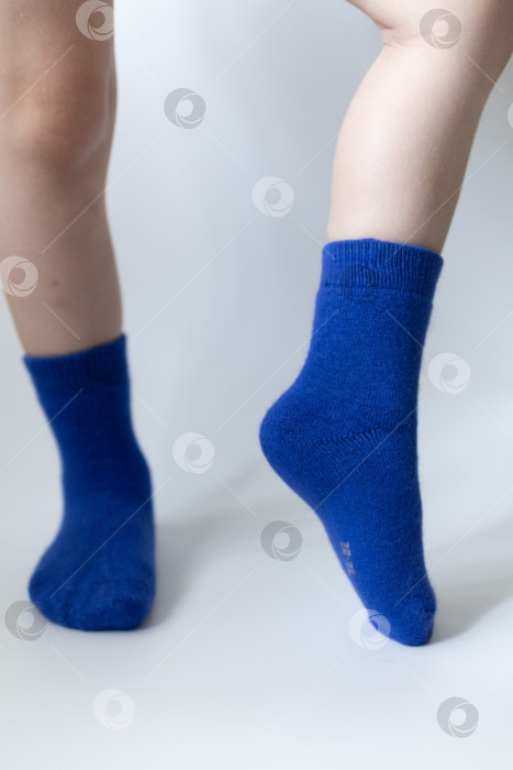 Скачать Детские ножки в синих носочках на белом фоне фотосток Ozero