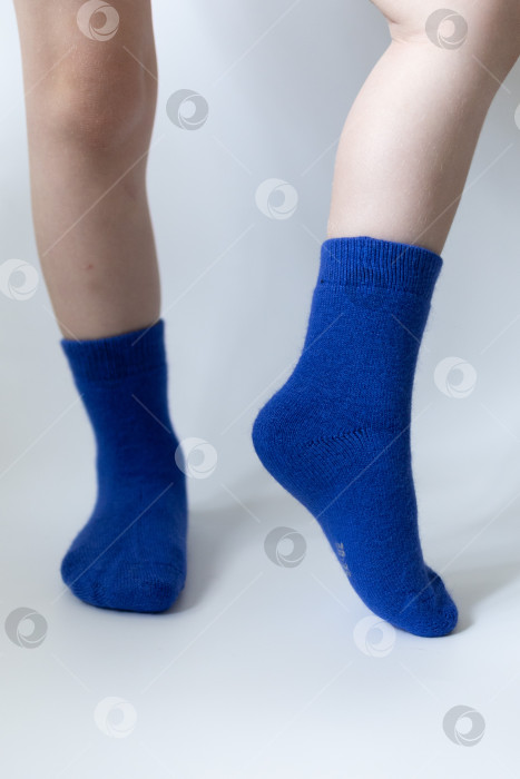 Скачать Детские ножки в синих носочках на белом фоне фотосток Ozero