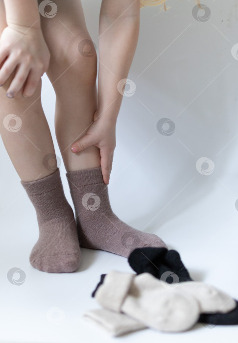 Скачать Детские ножки в теплых коричневых носочках на белом фоне фотосток Ozero