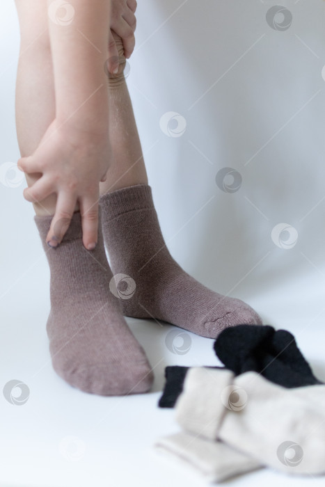 Скачать Детские ножки в теплых коричневых носочках на белом фоне фотосток Ozero