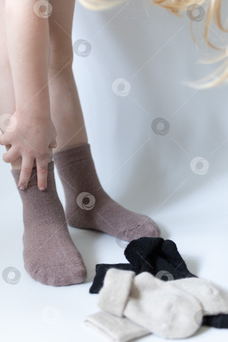 Скачать Детские ножки в теплых коричневых носочках на белом фоне фотосток Ozero