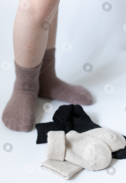 Скачать Детские ножки в теплых коричневых носочках на белом фоне фотосток Ozero