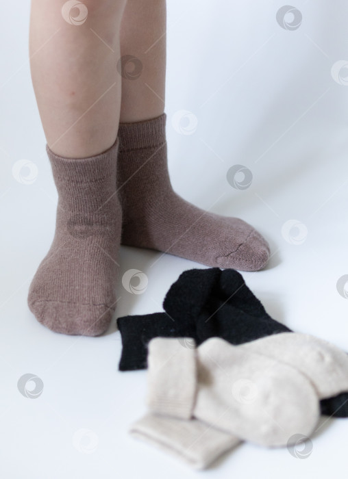 Скачать Детские ножки в теплых коричневых носочках на белом фоне фотосток Ozero