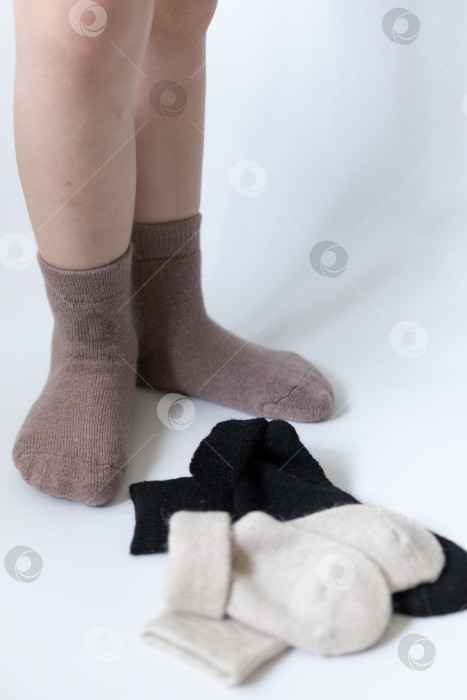 Скачать Детские ножки в теплых коричневых носочках на белом фоне фотосток Ozero