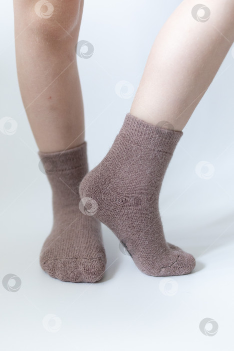 Скачать Детские ножки в теплых коричневых носочках на белом фоне фотосток Ozero