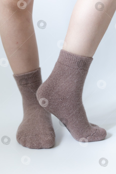 Скачать Детские ножки в теплых коричневых носочках на белом фоне фотосток Ozero