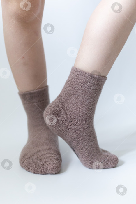 Скачать Детские ножки в теплых коричневых носочках на белом фоне фотосток Ozero