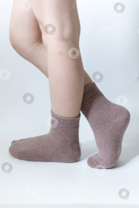 Скачать Детские ножки в теплых коричневых носочках на белом фоне фотосток Ozero