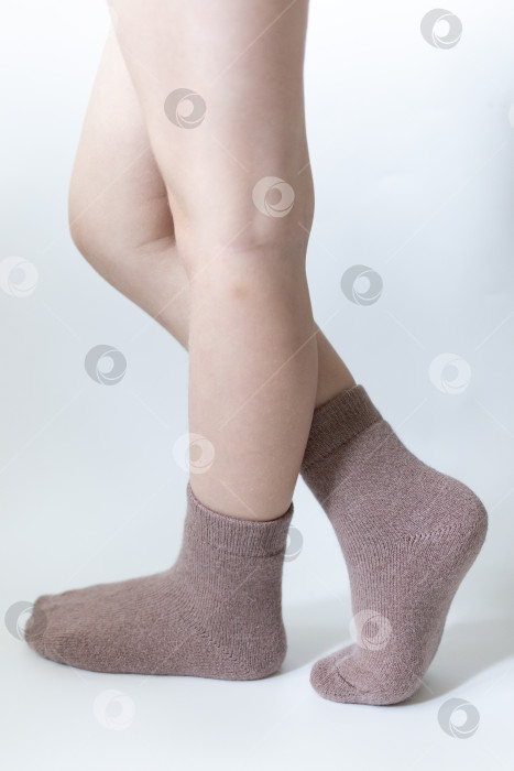 Скачать Детские ножки в теплых коричневых носочках на белом фоне фотосток Ozero