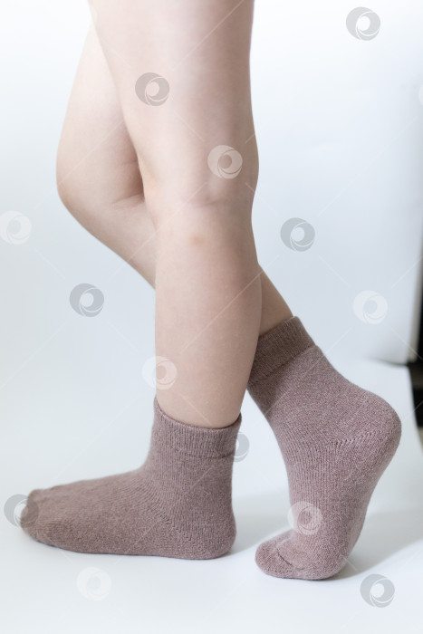 Скачать Детские ножки в теплых коричневых носочках на белом фоне фотосток Ozero