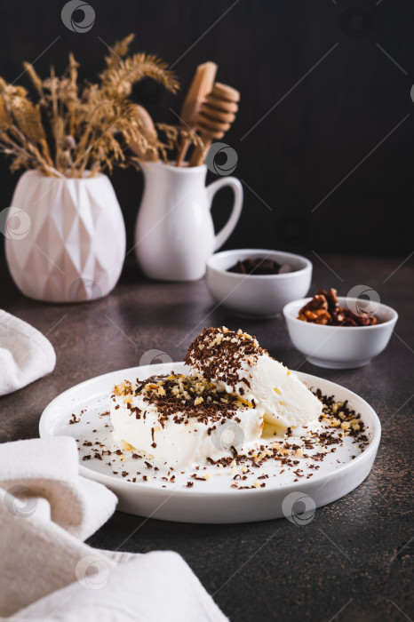 Скачать Мороженое, посыпанное шоколадной крошкой и орехами, на тарелке на столе в вертикальном положении фотосток Ozero