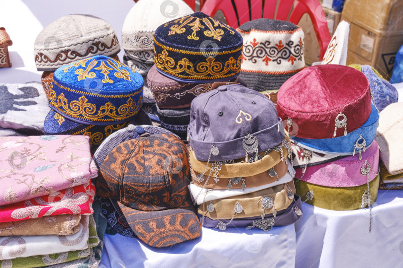Скачать Traditional kazakh skullcaps, embroidered headwear on market stall фотосток Ozero