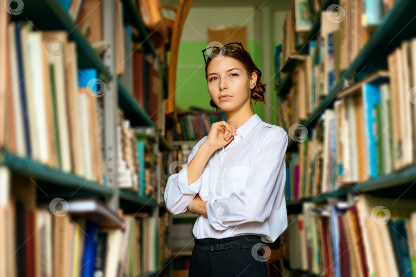 Скачать Симпатичная женщина в белой рубашке улыбается в библиотеке фотосток Ozero