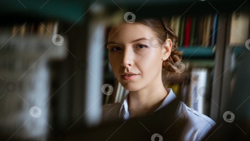 Скачать Портрет молодой женщины на фоне книг в библиотеке фотосток Ozero