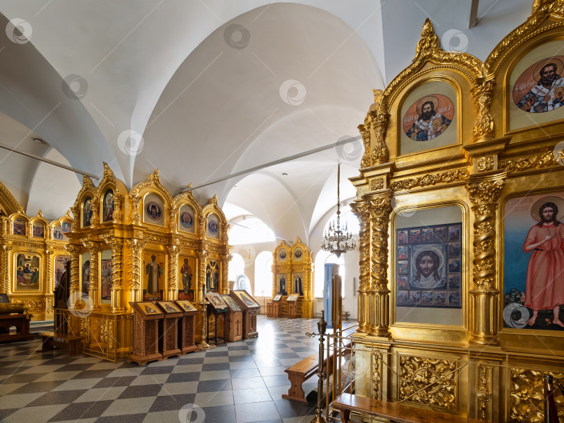 Скачать Иконы в золотых оправах в главном зале Троицкого собора Соловецкого монастыря. Высокие белые сводчатые потолки и шахматный пол дополняют величественный интерьер храма, освещаемого естественным светом из окон. фотосток Ozero