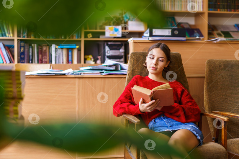 Скачать Посмотрите на красивую молодую женщину с интересной книгой в руках. Она читает фотосток Ozero