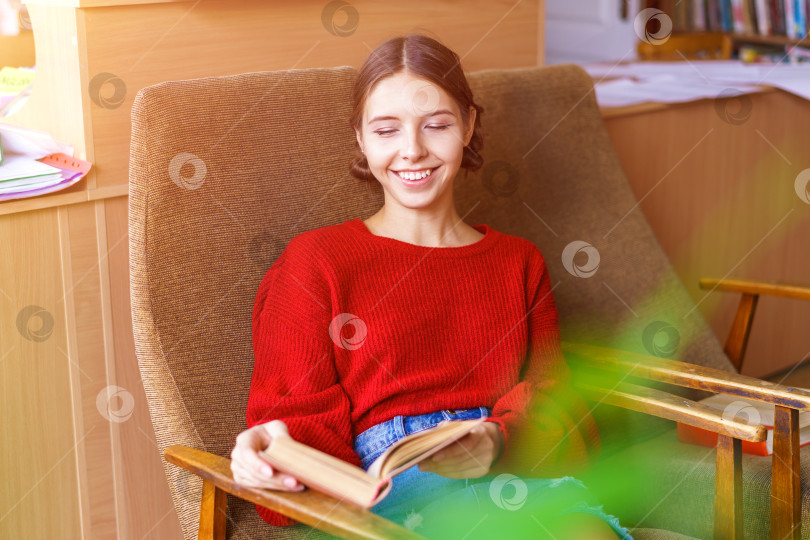 Скачать Веселая молодая брюнетка смеется над забавной историей из книги, счастливая фотосток Ozero