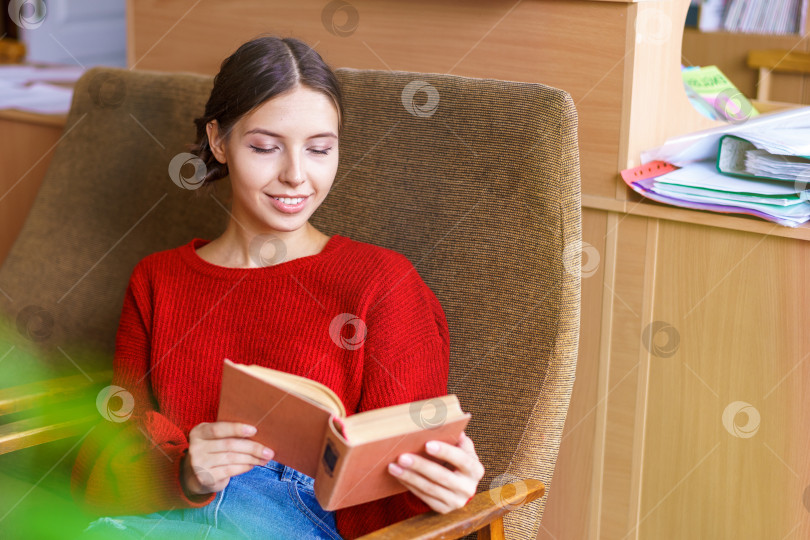 Скачать Веселая молодая брюнетка смеется над забавной историей из книги, счастливая фотосток Ozero