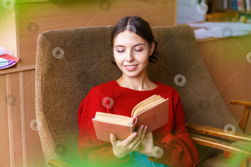 Скачать Посмотрите на красивую молодую женщину с интересной книгой в руках. Она читает фотосток Ozero