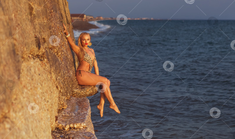 Скачать Женщина сидит на камне у океана. фотосток Ozero