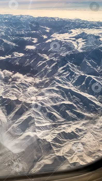 Скачать Из иллюминатора самолета виден горный хребет фотосток Ozero