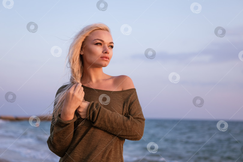 Скачать Блондинка стоит на пляже в зеленом свитере фотосток Ozero