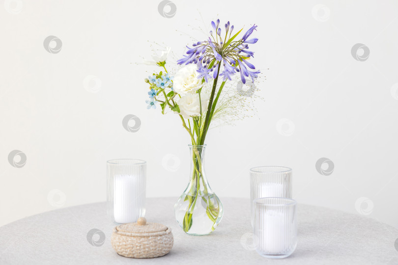 Скачать Красиво оформленная стеклянная ваза с яркими цветами и свечами на минималистичном столе для элегантного домашнего декора фотосток Ozero