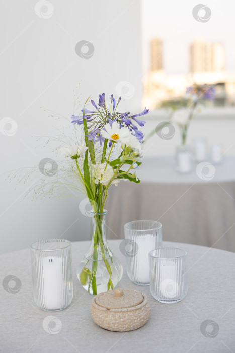 Скачать Красиво накрытый стол с цветочным украшением в центре и элегантными свечами создает безмятежную и располагающую атмосферу для посиделок фотосток Ozero