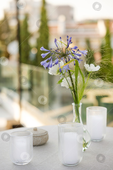 Скачать Элегантная сервировка стола свежими цветами и декоративными свечами создает безмятежную и располагающую атмосферу для посиделок в солнечный день. фотосток Ozero