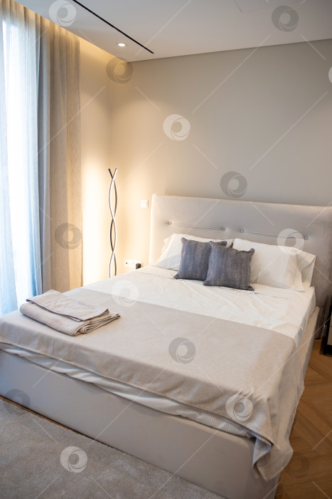 Скачать Современный и минималистичный интерьер спальни с использованием нейтральных тонов, мягкого текстиля и удобных постельных принадлежностей создает безмятежное жилое пространство фотосток Ozero