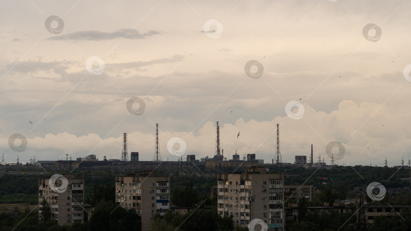 Скачать Промышленный горизонт возвышается над серыми квартирами под нависшими облаками фотосток Ozero