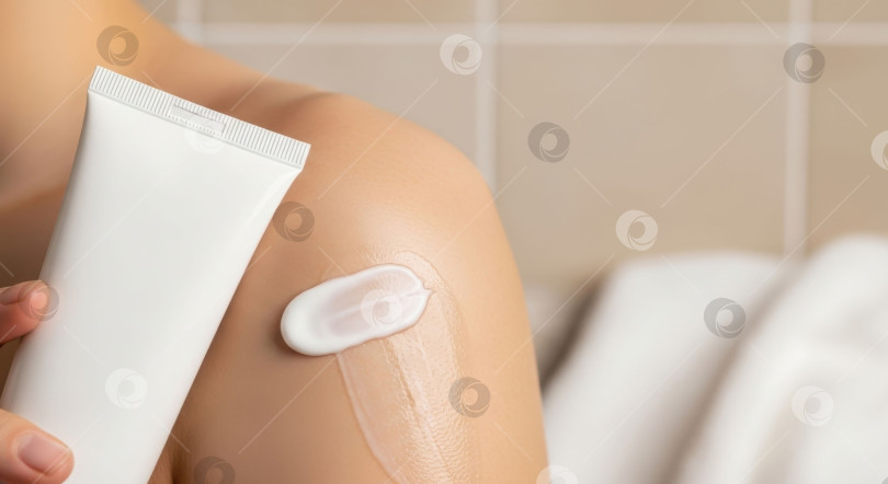 Скачать Женщина наносит белый увлажняющий крем из тюбика на свою гладкую кожу. Процедура по уходу за кожей тела. Концепция красоты и здоровья. фотосток Ozero