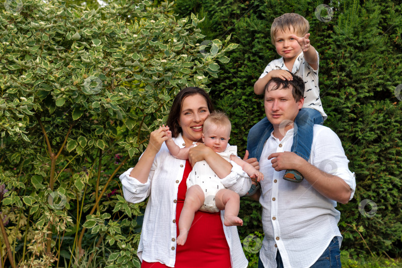 Скачать Toddler points while parents hold baby during garden portrait фотосток Ozero