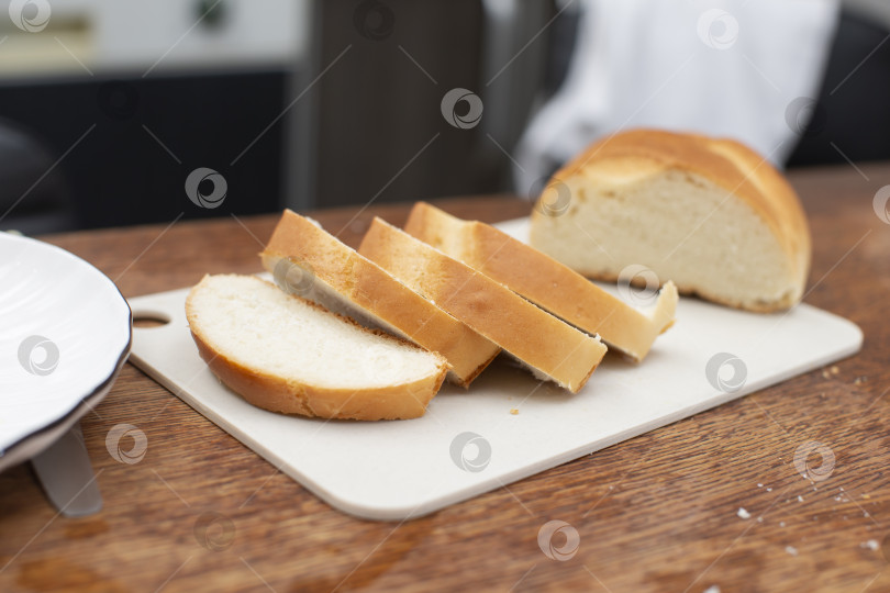 Скачать На деревянном столе лежат нарезанные кусочки белого хлеба. фотосток Ozero
