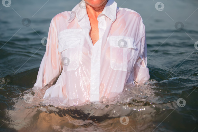 Скачать Из морской воды выходит неузнаваемая женщина в белой рубашке. фотосток Ozero