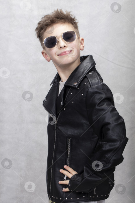 Скачать Красивый модный мальчик в кожаной куртке и очках улыбается, глядя в камеру. фотосток Ozero