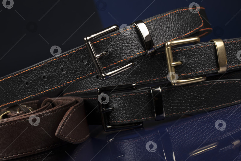 Скачать Группа черных кожаных ремней на синем фоне. фотосток Ozero
