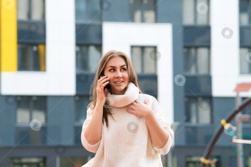 Скачать Девушка во дворе жилого комплекса разговаривает по телефону фотосток Ozero