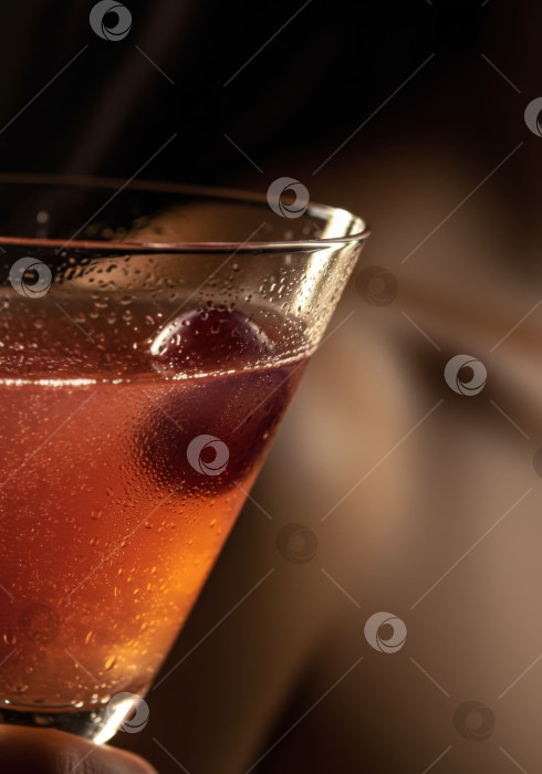 Скачать Крупный план женщины, держащей в руках холодный коктейль мартини с оливкой. Освежающий алкогольный напиток с каплями воды. фотосток Ozero