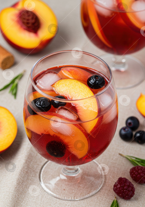 Скачать Домашний персиковый напиток-сангрия с черникой и льдом в бокале. Освежающий летний коктейль для оформления барного меню. фотосток Ozero